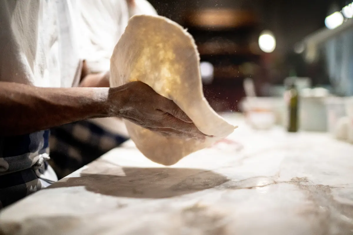 Hands kneading pizza dough for Nutella pizza.