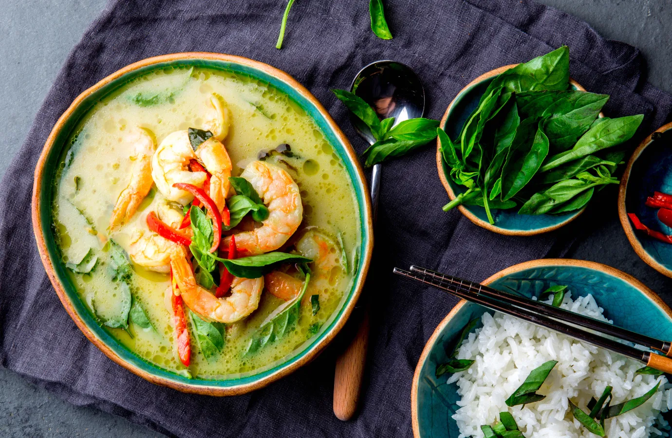 A vibrant display of fresh Thai curry ingredients including lemongrass, galangal, and kaffir lime leaves.