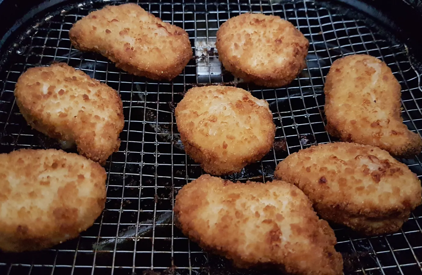 Preparing crispy chicken fries in an air fryer basket.